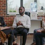 African american man making confession about addiction and rehabilitation with people at group